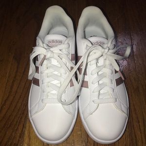 Adidas superstars sneakers with rose gold stripes.